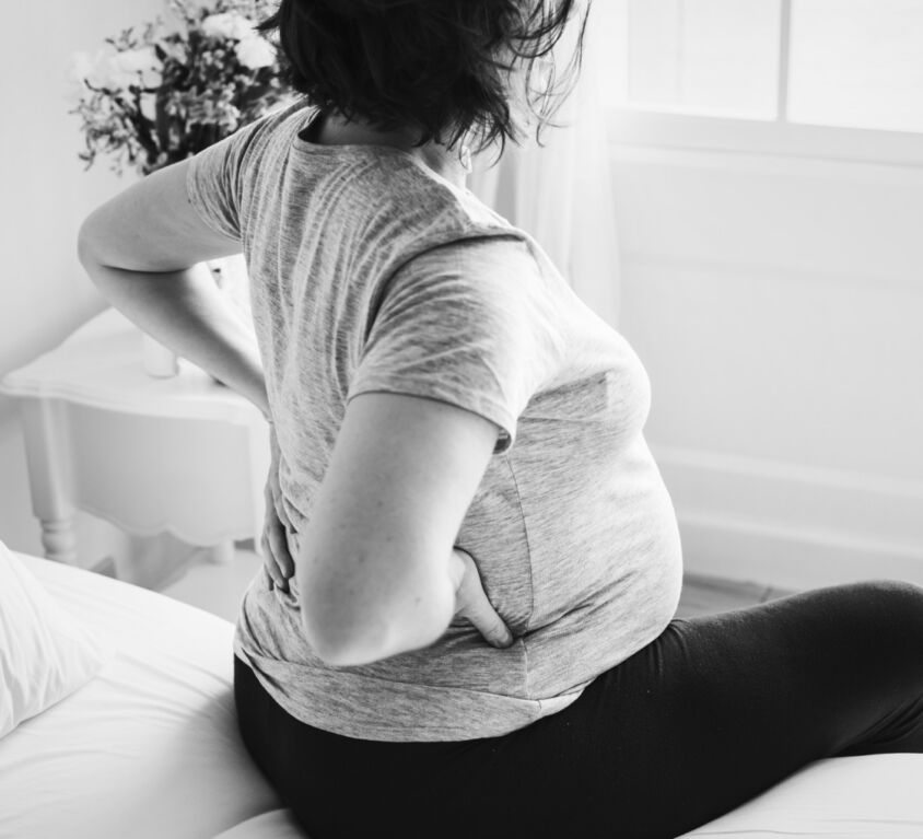 A pregnant woman sitting on a bed