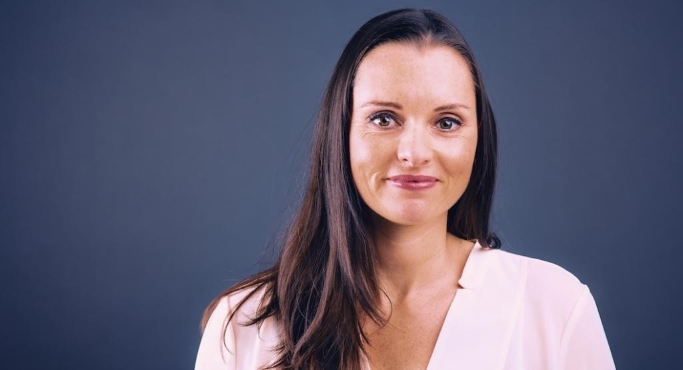 A woman with long hair is looking at the camera.