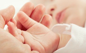A baby's hand is being held by a parent's hand.